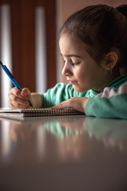 Ni A Seria Escribe Con Un Bol Grafo En Un Cuaderno Foto Gratis