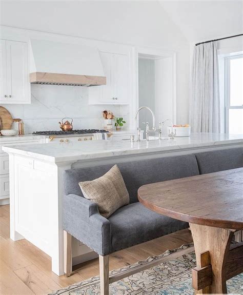 A Kitchen With An Island And Table In The Middle Of It Next To A Window