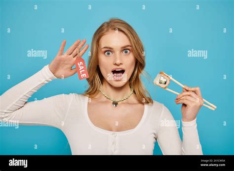 A Beautiful Blonde Woman Holds Chopsticks In Front Of Her Face Ready To Enjoy Delicious Asian