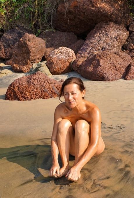 Naked Older Woman Diana Ananta Covers Her Feet In Beach Sand At Low