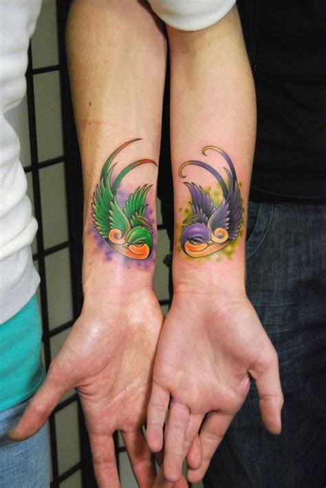 Two People Holding Hands With Tattoos On Their Arms And One Has A Bird