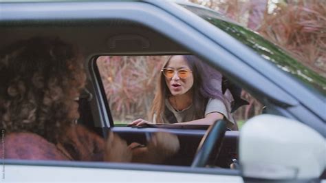 Two Friends Picking Up Friend For Road Trip In Car By Stocksy