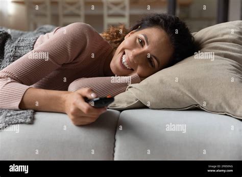 Happy Latina Female Lie On Cozy Couch Hold Tv Remote Stock Photo Alamy