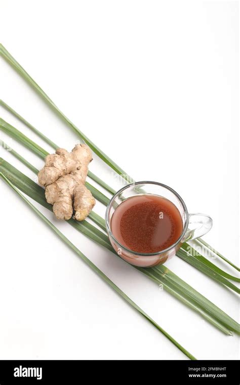 Glass Cup Of Hot Ginger Tea With Ginger Rhizome Root Sliced On White