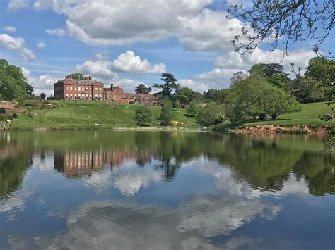 a large building sitting on top of a lush green hillside next to a lake ...