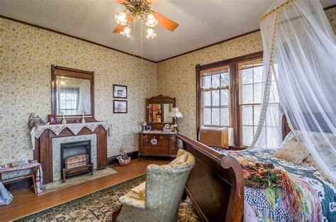 An Old Fashioned Bedroom With Floral Wallpaper And Antique Furniture