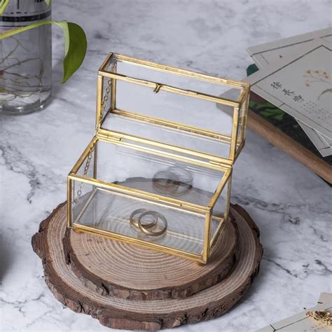 A Glass Jewelry Box Sitting On Top Of A Wooden Table