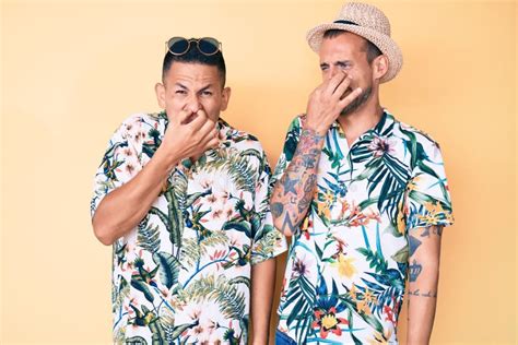 Joven Pareja Gay De Dos Hombres Con Sombrero De Verano Y Camiseta Hawaiana Oliendo Algo Afilado