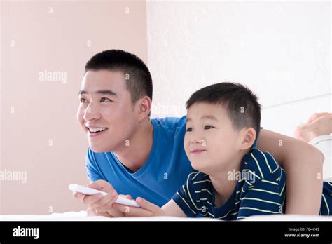 Padre e hijo viendo la televisión en la cama Fotografía de stock Alamy