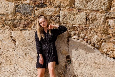 La Fille Blonde Regarde à Gauche En Robe Noire Sur Fond De Pierre Photo Gratuite