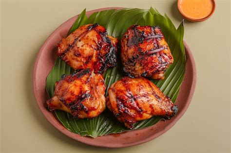 Premium Photo Grilled Chicken Thighs On Banana Leaf With Spicy Sauce In Clay Plate On Neutral