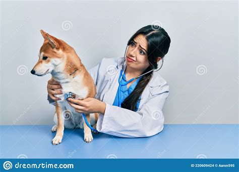 Beautiful Hispanic Veterinarian Woman Checking Dog Health Skeptic And