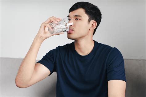handsome asian man drinking  glass  water   sofa  living room
