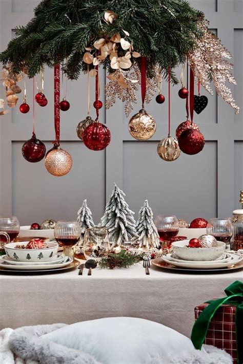 A Christmas Table Setting With Ornaments Hanging From The Ceiling And