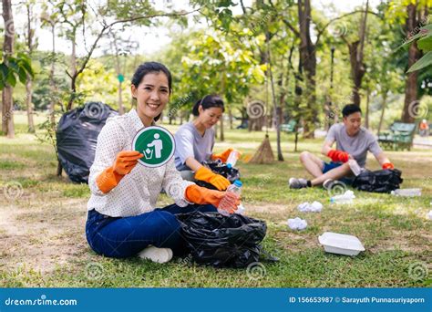 Young Asian Woman And Group Of Volunteers Wearing Orange Gloves And