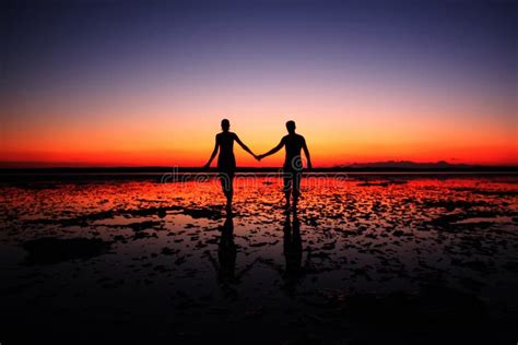 Amazing Silhouette Of Couple Walking Hand In Hand On Sunset Background