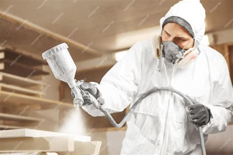 Premium Photo | Man in respirator mask painting wooden planks at workshop