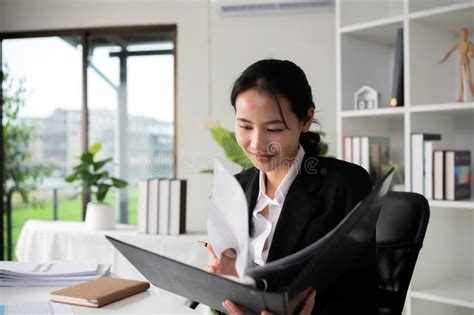 Focused Asian Female Accountant Doing Paperwork In Office With Plan