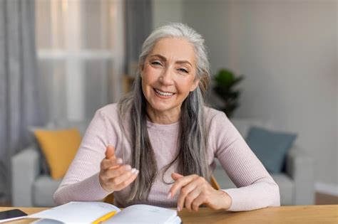 Une enseignante mature européenne souriante et souriante aux cheveux gris se réunit et regarde