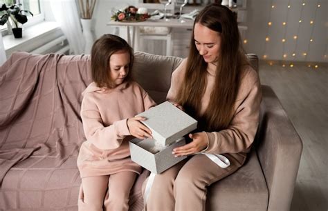 Belle Maman Et Sa Fille Sont Assises Sur Le Canapé Et Ouvrent Un Cadeau