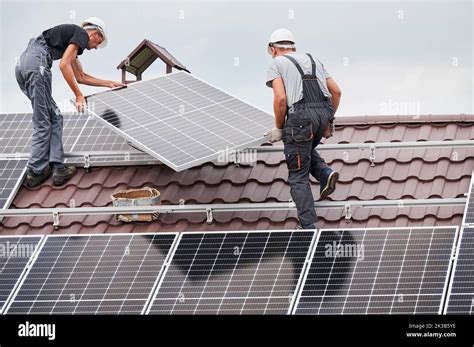 Men Technicians Lifting Up Photovoltaic Solar Moduls On Roof Of House