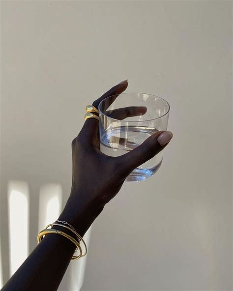 A Woman Holding A Glass With Her Hand In The Air While Wearing Gold