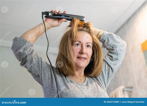 Femme Blanche Mature Fixant Ses Cheveux Devant Le Miroir Avec Un Dispositif De Lissage Des