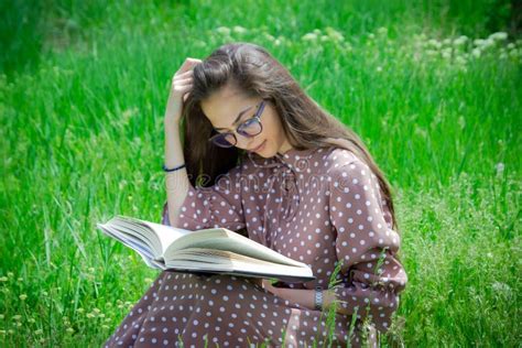 A Pretty Woman Sitting On The Grass Girl Reading A Book In The Park