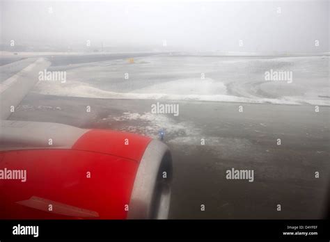 Looking Out Of Aircraft Window Over Snow Covered Foggy Airport Runway