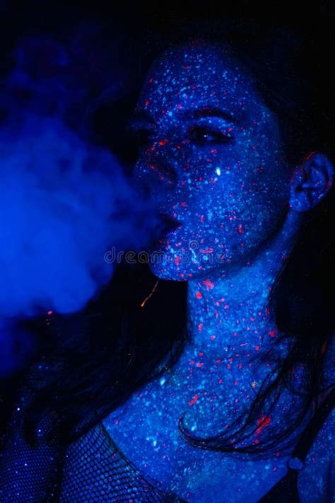 A Beautiful Young Girl With Makeup From Ultraviolet Paints Smokes