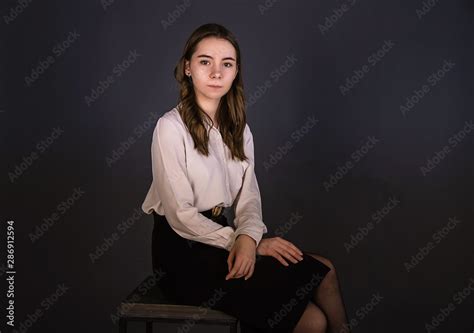 Portrait Of A Brunette Girl With Long Hair Sitting On A Chair Shooting In The Studio Plain
