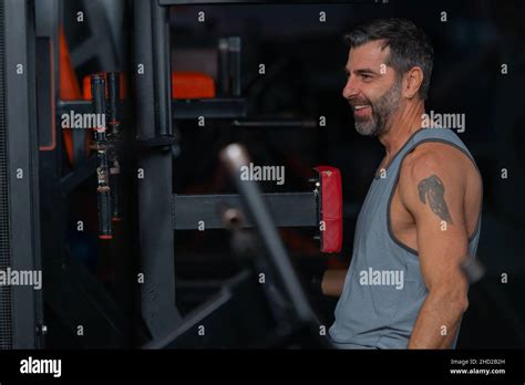 Happy Fit Mature Man Sitting And Resting Between Exercises In The Gym