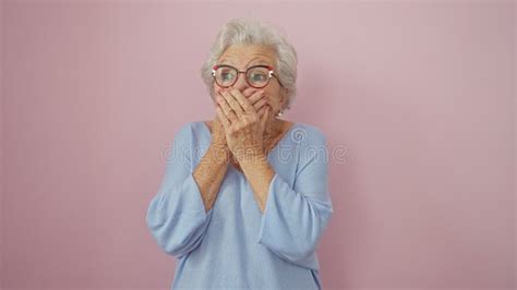 Shocked Mature Woman Grey Haired And Bespectacled Clasps Hand Over Her Mouth In Silent