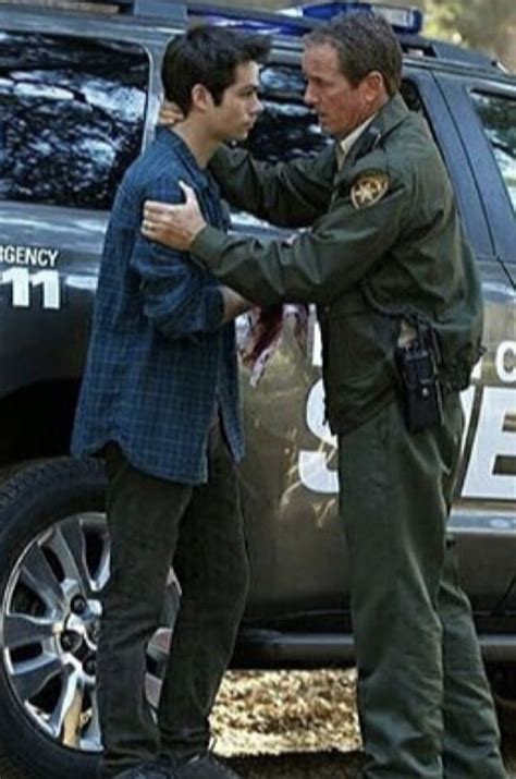 Two Men Standing Next To Each Other In Front Of A Police Car With Their