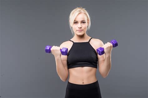 Jeune Fille Blonde Sportive Avec Un Corps Musclé En Forme Fonctionne Avec Des Haltères En Studio