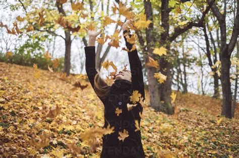 Happy Young Woman Throwing Autumn Leaves Into The Air Stock Photo