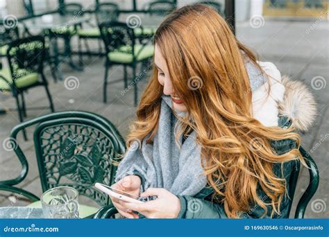 Jonge Blonde Meid Glimlacht Terwijl Ze Haar Smartphone In Een Bar Naakt Met Een Drankje Stock