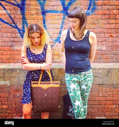 Two Women Standing In Front Of Brick Wall Stock Photo Alamy