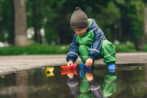 Free Photo | Funny kid in rain boots playing in a rain park