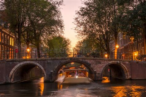 Pink Sunset On The Amsterdam Canal And A Boat Under The Bridge Stock