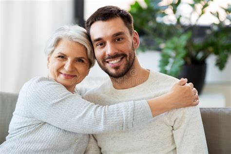 Madre Mayor Con El Hijo Adulto Que Abraza En Casa Imagen De Archivo