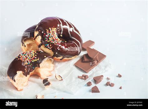 Chocolate Glazed Donuts With Sprinkles And Cinnamon On A White Wooden