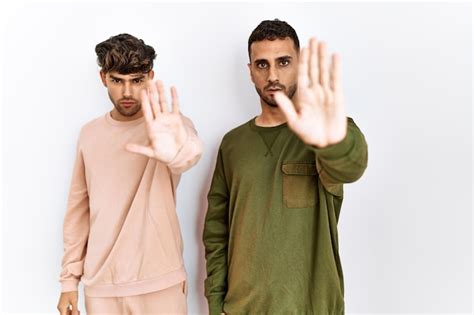 Joven Pareja Gay De Pie Sobre Fondo Blanco Aislado Haciendo Dejar De Cantar Con La Palma De La