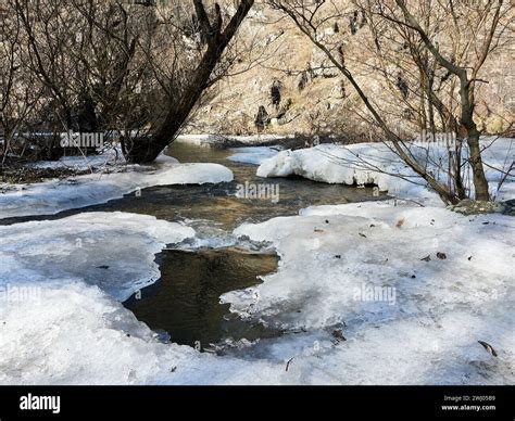 White Ice And Snow On Frozen River Water Flows Below Winter