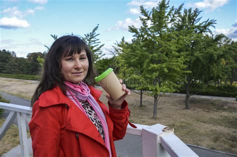 Cheerful Beautiful Brunette Woman In Red Coat Holding Disposable Coffee