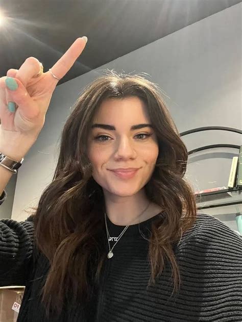 a woman with long brown hair is holding up her hand and smiling at the ...