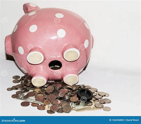 Pink Piggy Bank On Its Side With Coins And Bills Falling Out Of Opening