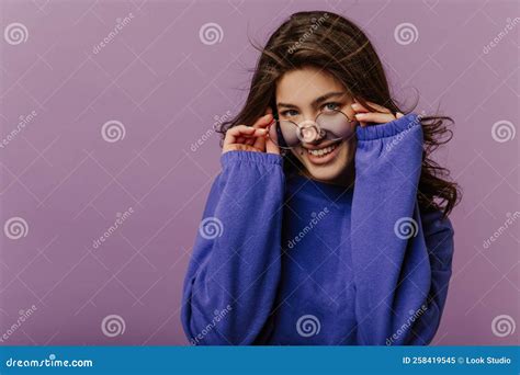 Cool Young Caucasian Girl Looks At Camera With Glasses Down On Nose Standing On Purple