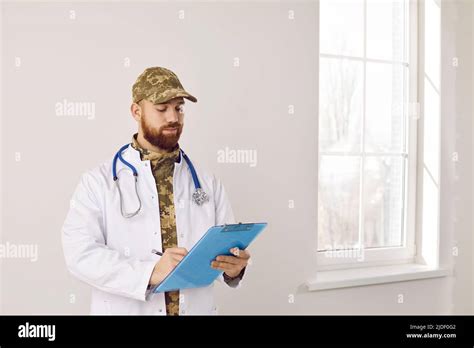 Portrait of military doctor in camouflage uniform and medical lab coat with clipboard Stock ...