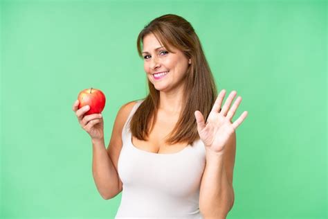 Mujer De Mediana Edad Con Una Manzana Sobre Un Fondo Aislado Saludando